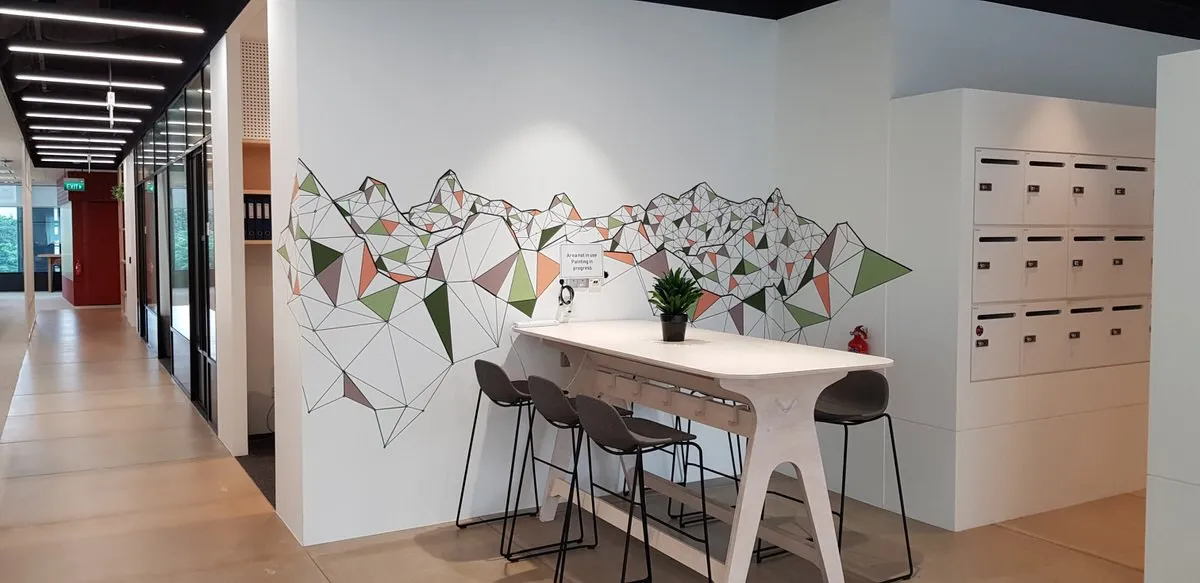 Wall mural of a geometric mountain range formed by bold black lines and earth-toned triangles in an office