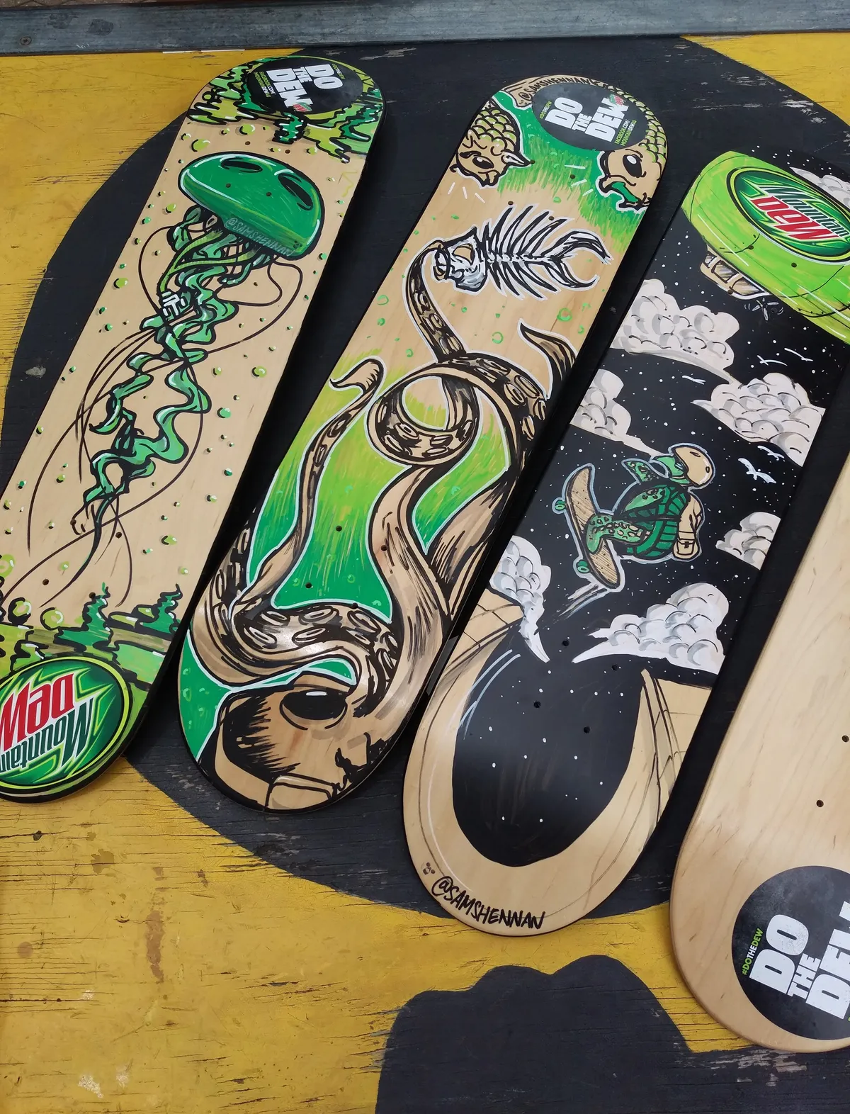 Four painted skateboards with Mountain Dew logos featuring bold line art of a jellyfish, tentacles, and a space turtle