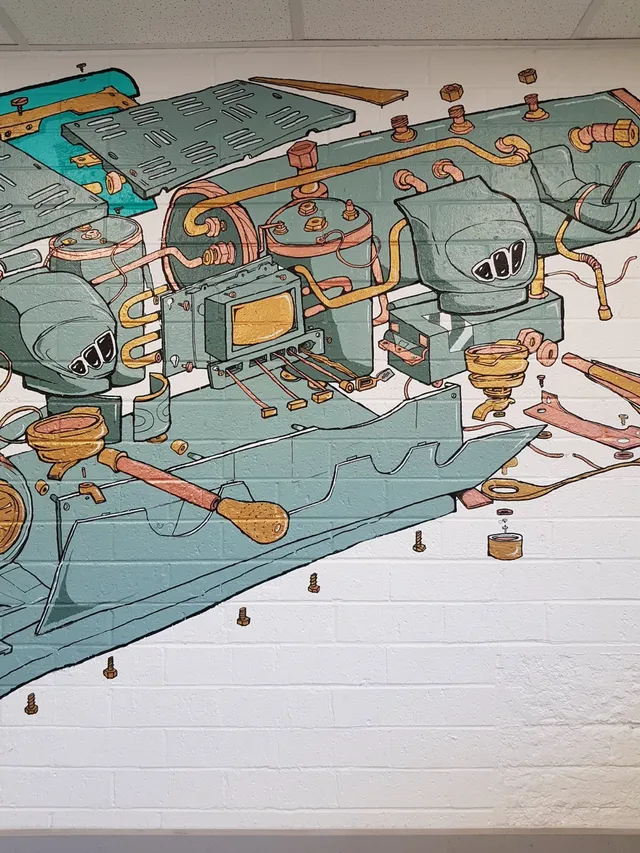 Mural on a white brick wall depicting a stylized exploded diagram of espresso machine parts and copper pipes