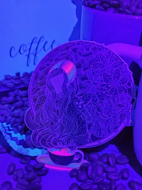 UV-illuminated sticker with psychedelic line art of a faceless woman emerging from a coffee cup, placed among coffee beans