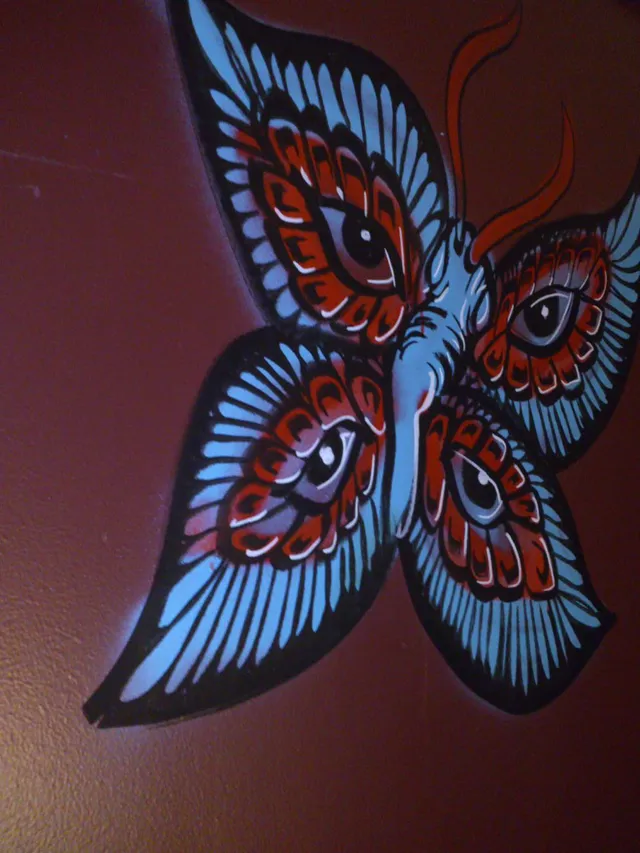 Painted mural of a psychedelic blue and red butterfly with large eye motifs on its wings