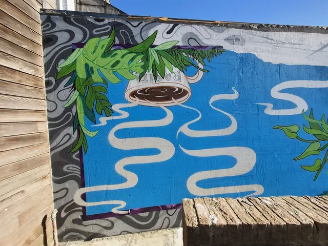 Mural of an upside-down coffee cup spilling wavy white lines onto a blue background framed by green leaves