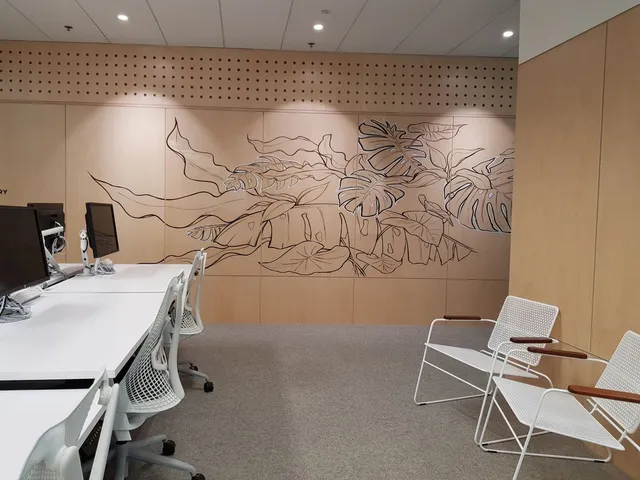 Line art mural of tropical leaves on a light wood paneled wall in an office setting