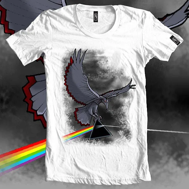 White t-shirt featuring an illustration of a grey bird holding a black prism refracting a rainbow beam