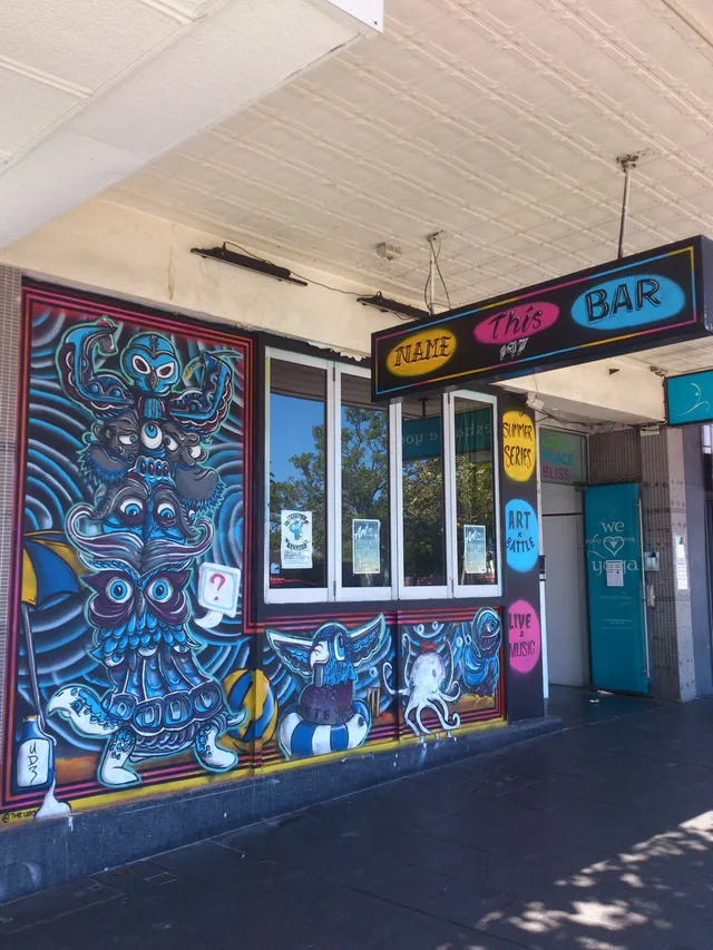 Exterior storefront mural featuring a vibrant blue totemic stack of psychedelic animal figures and an octopus