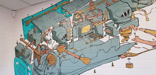 Mural on a white brick wall depicting an exploded, illustrated view of an espresso machine and its internal parts