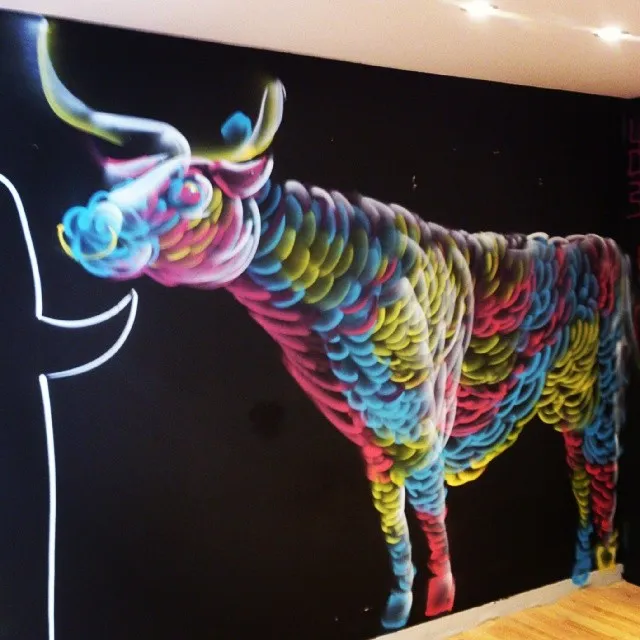 Psychedelic mural of a colorful bull made of overlapping curved strokes on a black wall