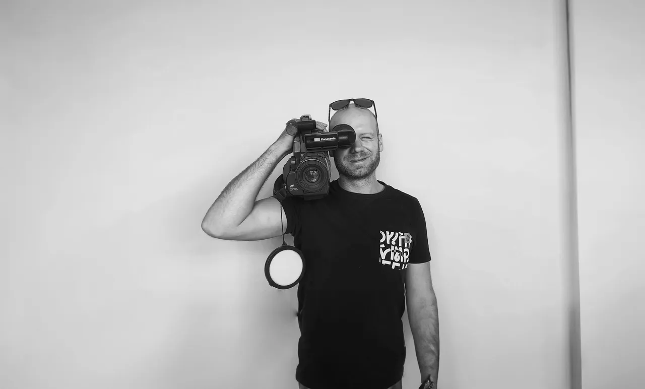 Black and white portrait of a man holding a video camera on his shoulder and looking through the viewfinder