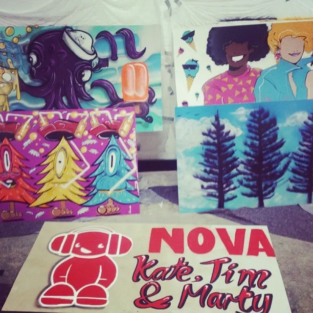 Painted boards featuring an octopus, cyclops trees, portraits, pine trees, and a Nova Kate, Tim & Marty sign