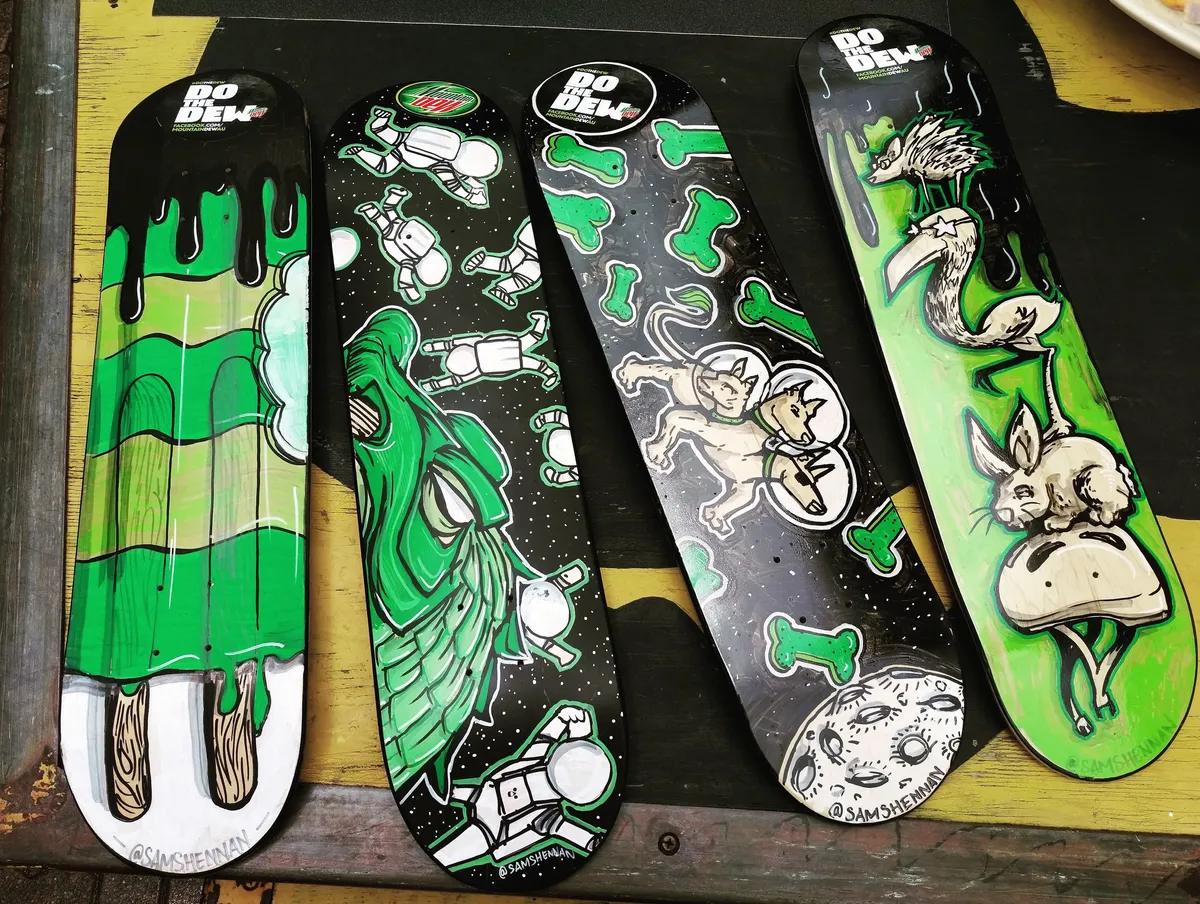 Four hand-painted skateboards featuring bold black, white, and neon green psychedelic space and animal illustrations