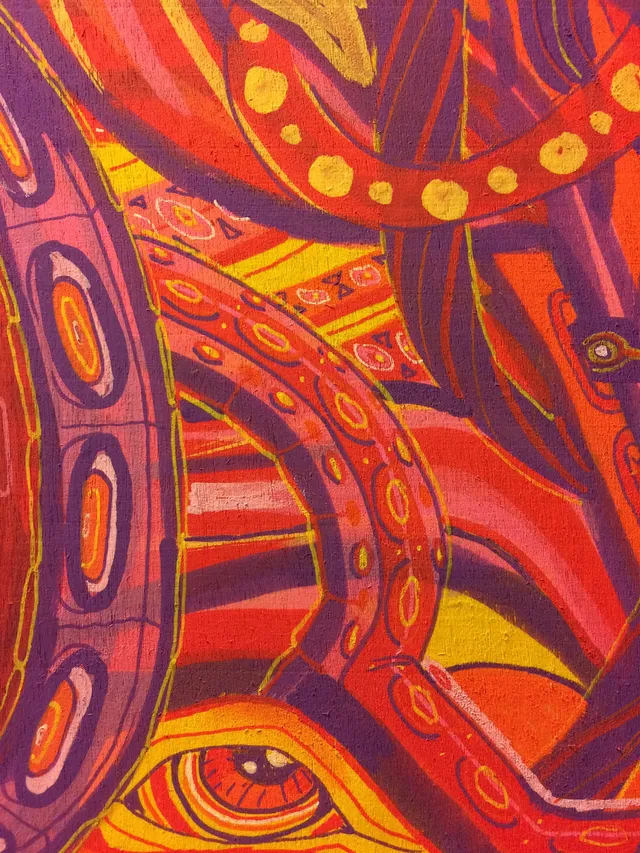 Psychedelic painting detail of swirling red, orange, and purple tentacles and a stylized eye